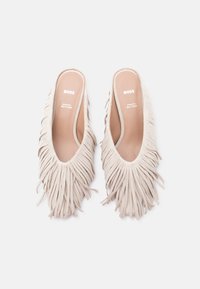 Chaussures beige à enfiler avec des détails de longues franges couvrant le dessus, arborant la marque "BOSS" à l'intérieur des semelles intérieures souples et rembourrées.
