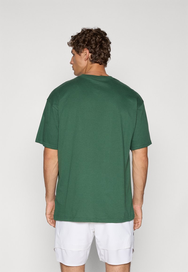 T-shirt in cotone verde con una vestibilità comoda e maniche corte, caratterizzato da un collo rotondo e una texture liscia, mostrato di schiena.