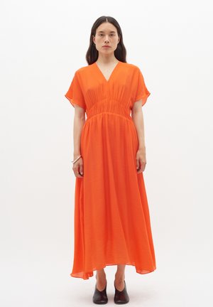 Maxi dress in bright orange fabric, featuring a deep V-neck, short flutter sleeves, and a fitted waist with gathered detail.