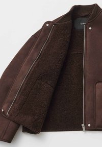 Giacca bomber marrone con interno morbido e peloso. Presenta una chiusura con cerniera, collo a costine e dettagli con tasche laterali.