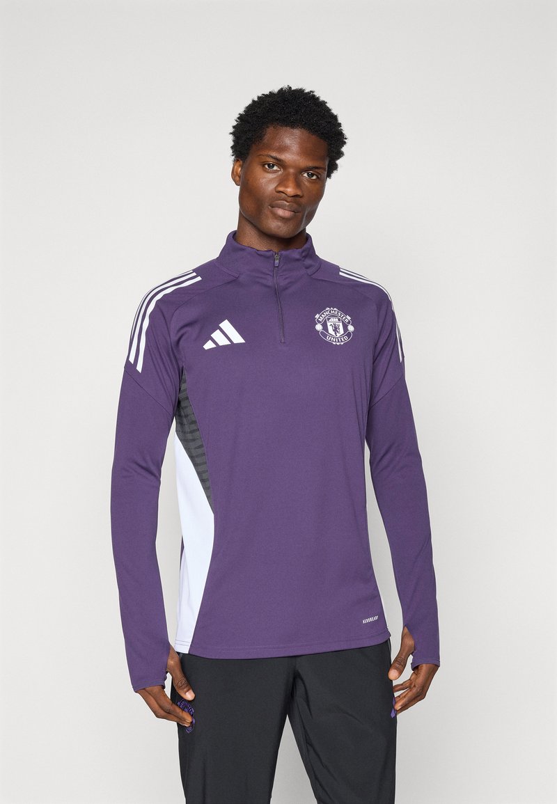 Purple long-sleeve athletic top with half-zip, Manchester United logo, white and black side accents, and textured fabric inserts.