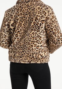 Leopardenmuster Faux-Fur-Jacke, weiche Textur, runder Kragen, lockere Passform, lange Ärmel, elastischer Saum, kombiniert mit schwarzen Hosen.
