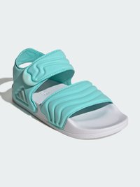 Turkusowa sandałka na płaskim obcasie z teksturowanymi paskami i białą podeszwą. Charakteryzuje się ergonomicznym kształtem, regulowanymi paskami na rzep oraz gładkim wykończeniem.