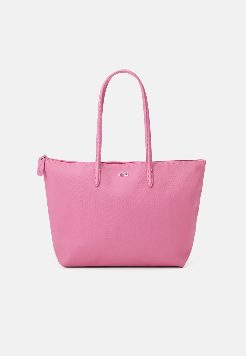 Roze tote bag gemaakt van glad synthetisch materiaal, voorzien van twee lange handvatten en een kleine merkritsaanhanger aan de zijkant.