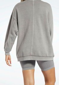 Grå oversized sweatshirt med ribbade muddar och nederkant, i kombination med grå figurnära shorts. Mjuk material med en slät textur.