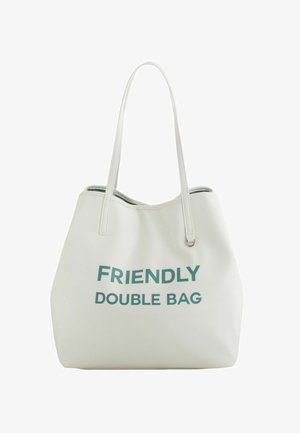 Hvid totebag lavet af tekstureret materiale med teksten "FRIENDLY DOUBLE BAG" trykt med fede teal-bogstaver. Dobbeltremme til bæreevne.