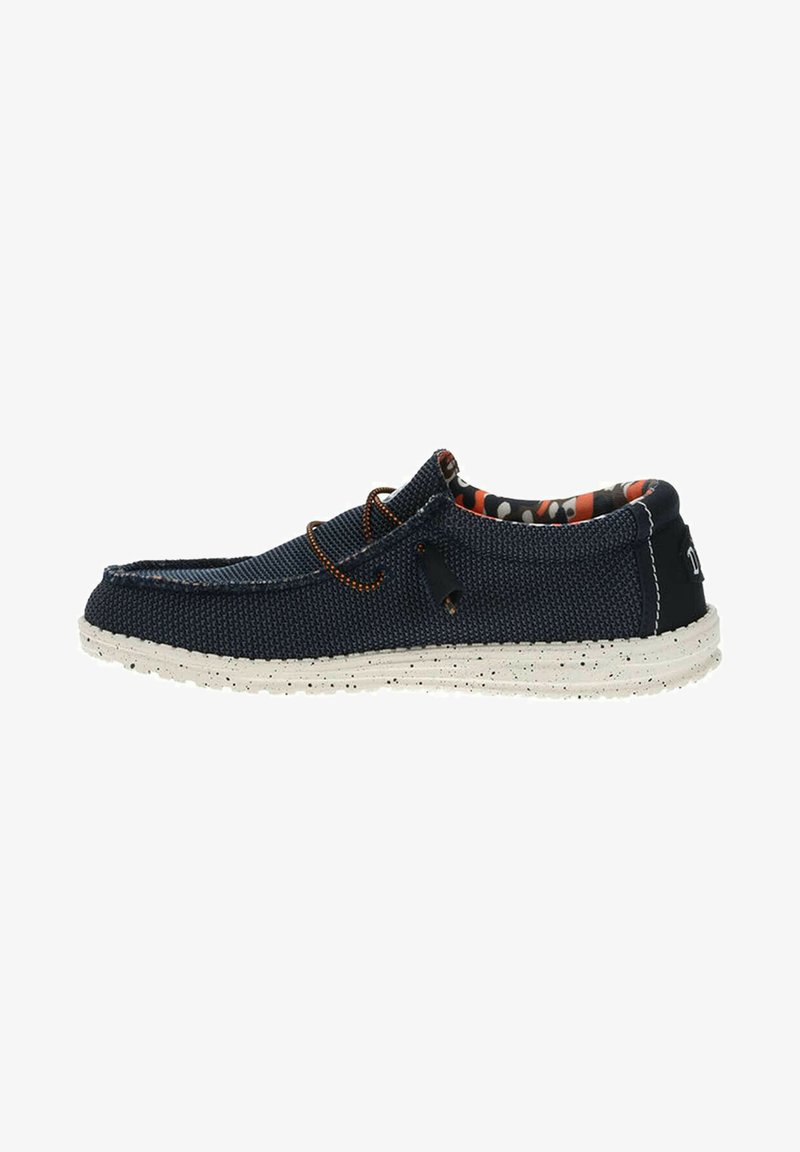 Scarpa slip-on in tessuto blu navy con tomaia strutturata, suola bianca maculata in contrasto e foderato interno a fantasia. Presenta un lacci di accento arancione.