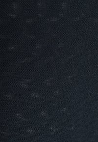 Tmavě modrá texturovaná tkanina s jemným vzorem; vazba je drobná a mírně odrážející světlo, což vytváří měkký vzhled.