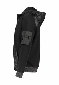 Chaqueta negra con capucha forrada de malla, acentos de tela brillante, cierre de cremallera, puños elásticos y un bolsillo con solapa en la manga.
