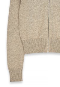 Beige stickad kofta med dragkedja, ribbade ärmslut och nederkant, med en mjuk textur och en enkel, klassisk design.