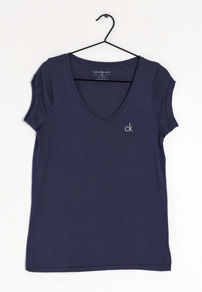 Navy blue cotton t-shirt with short sleeves, v-neckline, and a small white "ck" logo on the left chest. Hangs on a black hook.