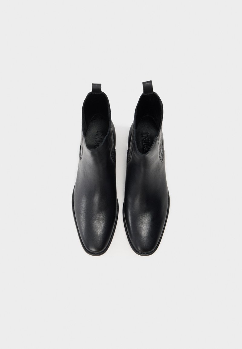 Schwarze Leder-Stiefeletten mit glatter Oberfläche, spitzem Zehenbereich, kleinem Zuglaschen und elastischen seitlichen Akzenten für Flexibilität.
