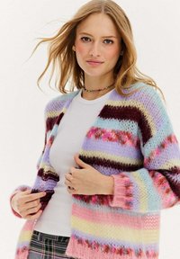 Sweter w robótkach z wielokolorowymi paskami w odcieniach różu, fioletu, niebieskiego i kremowego. Miękka, puszysta tekstura, z otwartym przodem i prążkowanymi mankietami.