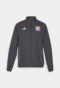 Svart idrettsjakke med gullaksenter, med full glidelås, høy krage og blå og røde horisontale striper på skuldrene. Olympique Lyonnais-logo.