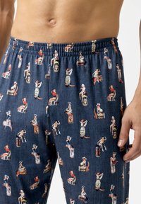 Heren nachtcostuum shorts in marineblauw, gemaakt van zachte stof, met een herhalend motief van vintage pin-up illustraties en verschillende gekleurde accenten.