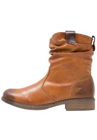 Bottine en cuir marron avec un tige lâche, bout rond et un petit talon bloc. Présente une sangle d'accent marron foncé en haut.