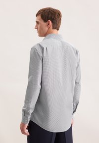 Camicia button-up grigia chiara con un sottile motivo geometrico, maniche lunghe e polsini a doppio bottone, dotata di colletto classico e vestibilità rilassata.