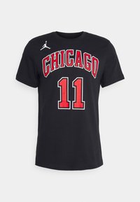 Camiseta de algodón negra con el texto en negrita "CHICAGO" en rojo y el número "11" con contorno blanco. Incluye un pequeño logo blanco en la parte superior izquierda.
