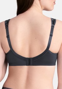 Dark gray bra with adjustable straps, a smooth texture, and a clasp closure. Straps feature a floral pattern. Back design is seamless.