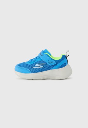Zapatilla deportiva azul para niños con parte superior de malla, tira de velcro, forro interior verde neón, suela blanca gruesa y asa negra en el talón.