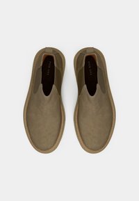 Brune slip-on sko med en glat ruskindsfinish, elastiske sidepaneler og en tekstureret gummisål. Minimalistisk design uden synlige logoer.