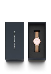 Rose gold metal watch with a mesh strap inside a navy box; round face with a light pink dial and minimalist hour markers.