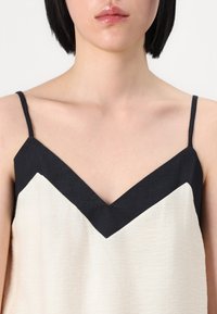 Top con estampado de chevron en blanco y negro, con tirantes finos, que presenta un escote en V y una tela ligera de textura.