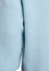 Maglione azzurro chiaro realizzato in morbido tessuto a coste. Presenta una vestibilità relaxed con leggere aperture ai lati per facilitare i movimenti.