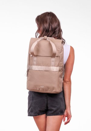 Beige batoh vyrobený z hladké tkaniny s horním víkem a dvěma ramenními popruhy. Obsahuje logo pásek a horní rukojeť pro snadné přenášení.