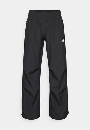 Pantalons noirs, légers et imperméables avec une taille élastique, des poches latérales et des poignets ajustables. Présente un logo blanc sur la cuisse gauche.