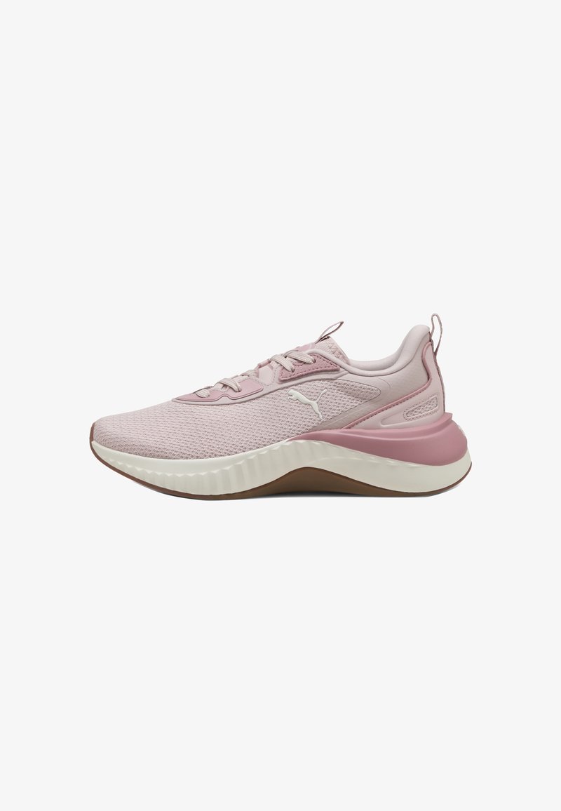 Scarpa sportiva di colore rosa chiaro con tomaia in rete, suola in gomma e dettagli testurizzati. Presenta un colletto imbottito e un sistema di allacciatura simmetrico.