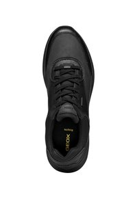 Svart sneaker med slät läder och mesh-material, med en rund tå, texturerade snören och en synlig logo inuti.