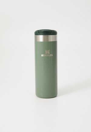 Insulated travel mug in matte green, stainless steel collar, and dark green lid. Features a textured surface and engraved logo.