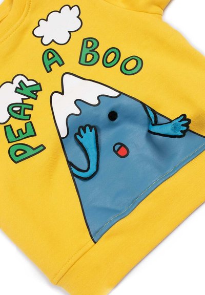 Felpa gialla con grafica di una montagna blu, mani alzate e un'espressione facciale, con nuvole sopra e il testo "PEAK A BOO" in verde.