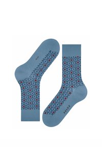 Paar blaue Socken mit dunkelblauem Gittermuster und kleinen roten Sternformen, Markenname "Falke" im Sohlenbereich.