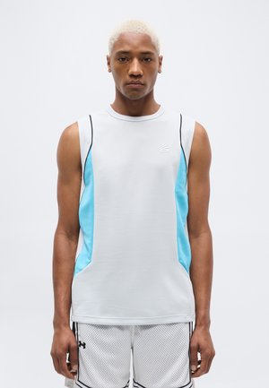 Mand med kort blondt hår iført ærmeløs hvid sportstrøje med blå sidepaneler og hvide basketballshorts i mesh.