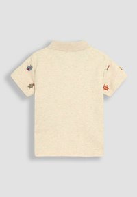 Valkoisenvärinen lyhythihainen polo-paita, jossa on kauluspääntie. Paidassa on värikkäitä brodeerattuja hyönteisdesignsejä hihoissa.