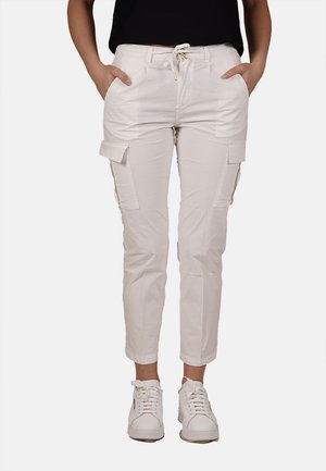Pantaloni cargo bianchi con vita regolabile, tasche laterali e caviglie stringate. Tessuto liscio e materiale resistente, abbinati a sneakers bianche.