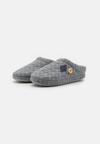 Chaussons gris tricotés avec une texture tissée, dotés d'un bout arrondi, d'un talon bas et d'un bouton décoratif en bois sur le côté.