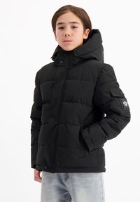 Zwarte gewatteerde jas met hoge kraag en capuchon, voorzien van drukknoopsluiting en een zijzak. Soepele textuur, op maat gemaakte pasvorm.