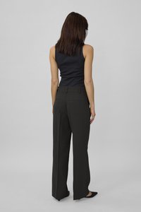 Pantaloni neri a vita alta con un design a gamba dritta, dotati di due tasche posteriori e cuciture sottili. Abbinati a un top aderente nero.