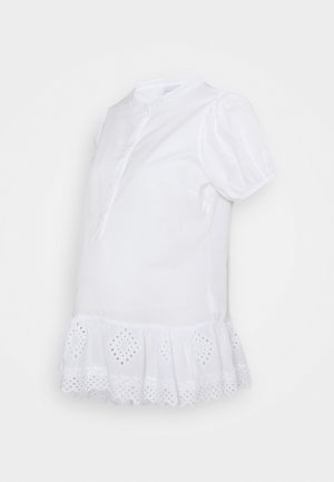 Biała bluzka z krótkim rękawem, wykończona koronką typu ażurowego na dole, z bufkami na rękawach oraz małym stojącym kołnierzykiem i częściowym, przednim zapięciem na guziki.