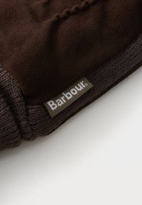 Pruun nahast kinnas koos kudumisega mansetiga; sildil on tekst "Barbour". Sile tekstuur õrna sädelusega; struktureeritud kuju.