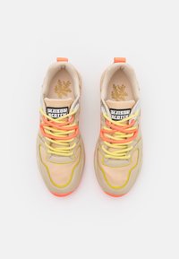 Beige sneakers with yellow and pink accents. Features a textured upper, contrasting laces, and a padded collar. Logo on tongue.