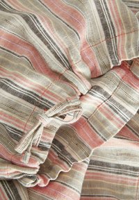 Gestreepte stof met zachte tinten van roze, beige en bruin, met een textuurafwerking en gerimpelde details die zachte plooien en rimpelingen creëren.