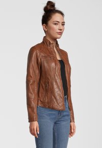 Braune Lederjacke mit Stehkragen, Reißverschluss und gesteppten Schulterdetails. Verfügt über Seitentaschen und eine taillierte Passform.