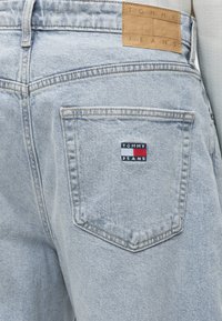 Φωτεινή μπλε τζιν πίσω τσέπη με κεντημένο λογότυπο Tommy Jeans και ετικέτα από ταμπά δέρμα στη μέση.