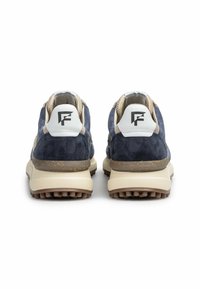 Ein Paar marineblaue und beige Sneakers mit weißen Fersenlaschen, die ein stilisiertes schwarzes "F"-Logo tragen, von hinten auf einem weißen Hintergrund betrachtet.