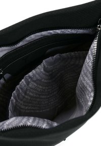 Interno di borsa nera con rivestimento grigio liscio caratterizzato da testo ripetuto. Chiusura con zip e tasche interne per l'organizzazione. Esterno in tessuto testurizzato.