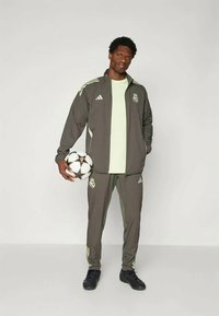 Tumehall hallituspüksid kerge rohelise särgiga, millel on valged aktsendid ja meeskonna logo, koos mustade jalgpallikinnaste ja jalgpalliga.